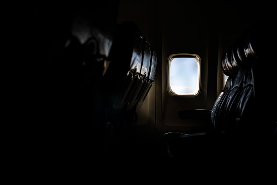 Dark airplane cabin with an illuminated window view during flight.